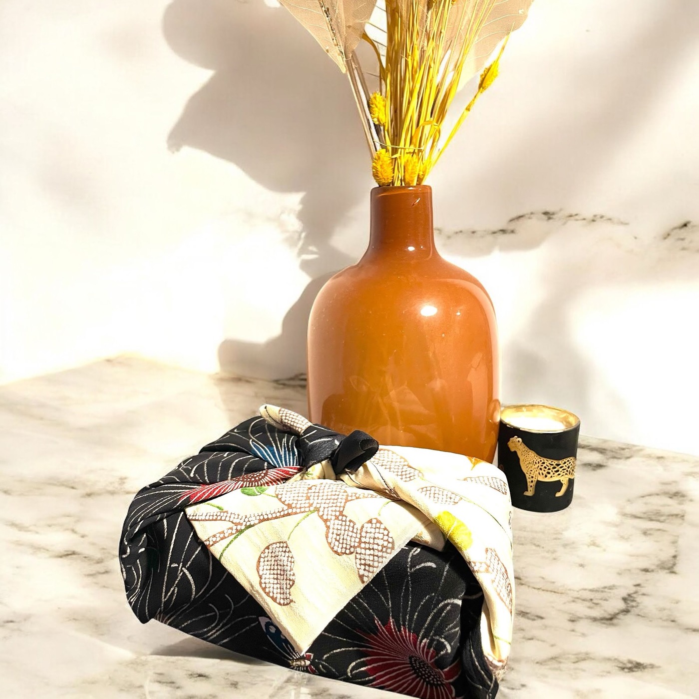 Objet enveloppé dans un furoshiki de soie, posé sur un plateau de marbre
